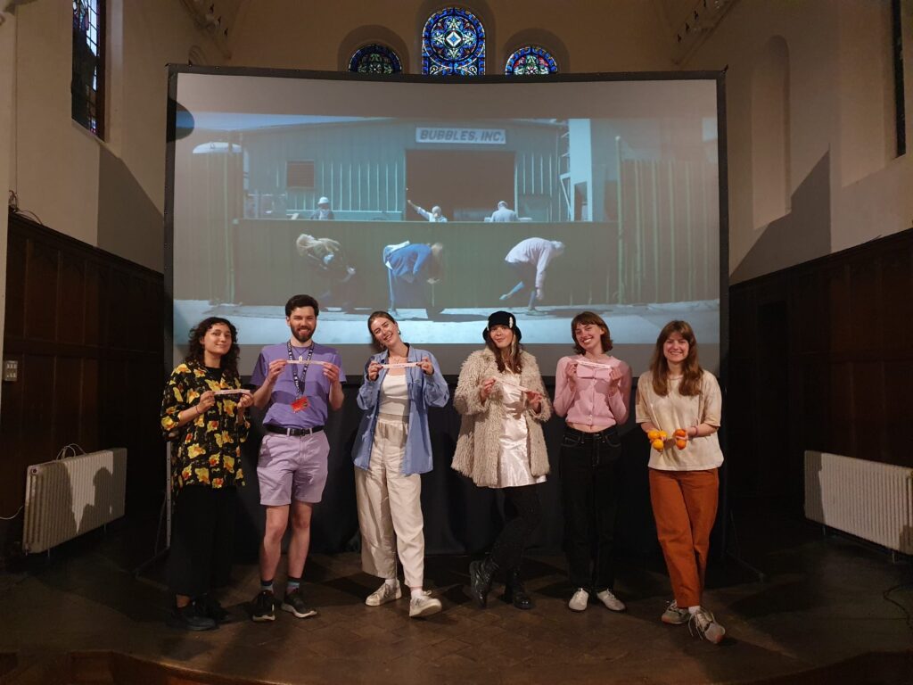 A group of young people standing in front of a cinema screen in a church setting.