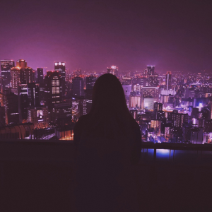 A photo of Laura Reyes looking out over a nightscape of a city